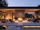 a modern outdoor living space featuring a sleek, contemporary fireplace surrounded by stylish lounge furniture, illuminated by warm ambient lighting during a cozy evening gathering.