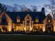 a beautifully illuminated georgia home exudes warmth and charm in the evening, showcasing meticulously chosen outdoor lighting fixtures that enhance its architectural features against a sophisticated urban backdrop.