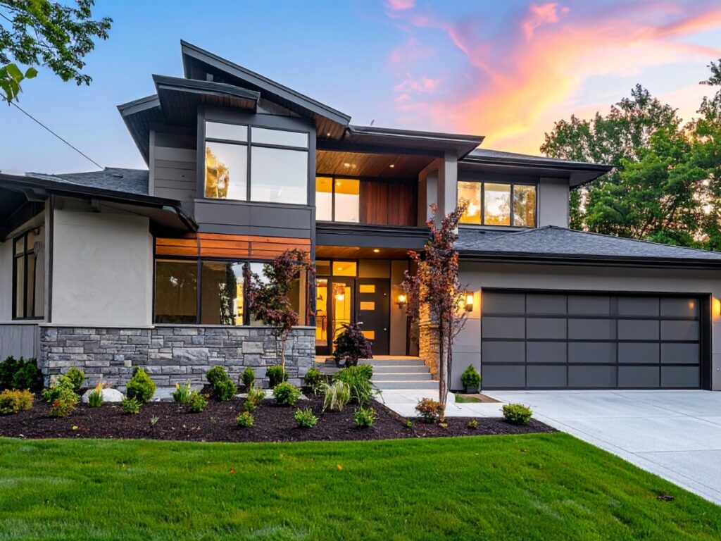 Modern two-story house with large windows, stone and wood exterior accents, triple garage, and landscaped yard where you can choose landscape style—all set against a beautiful sunset sky.